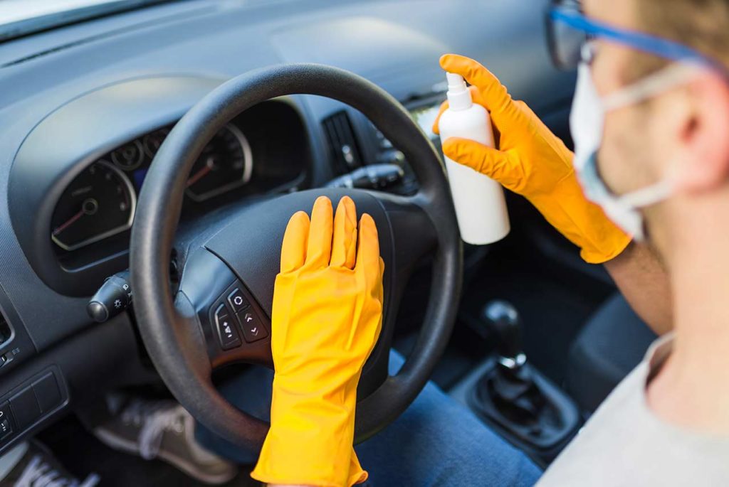 Conductor desinfectando el interior de un coche en casa utilizando todas las medidas de seguridad frente a la Covid.19