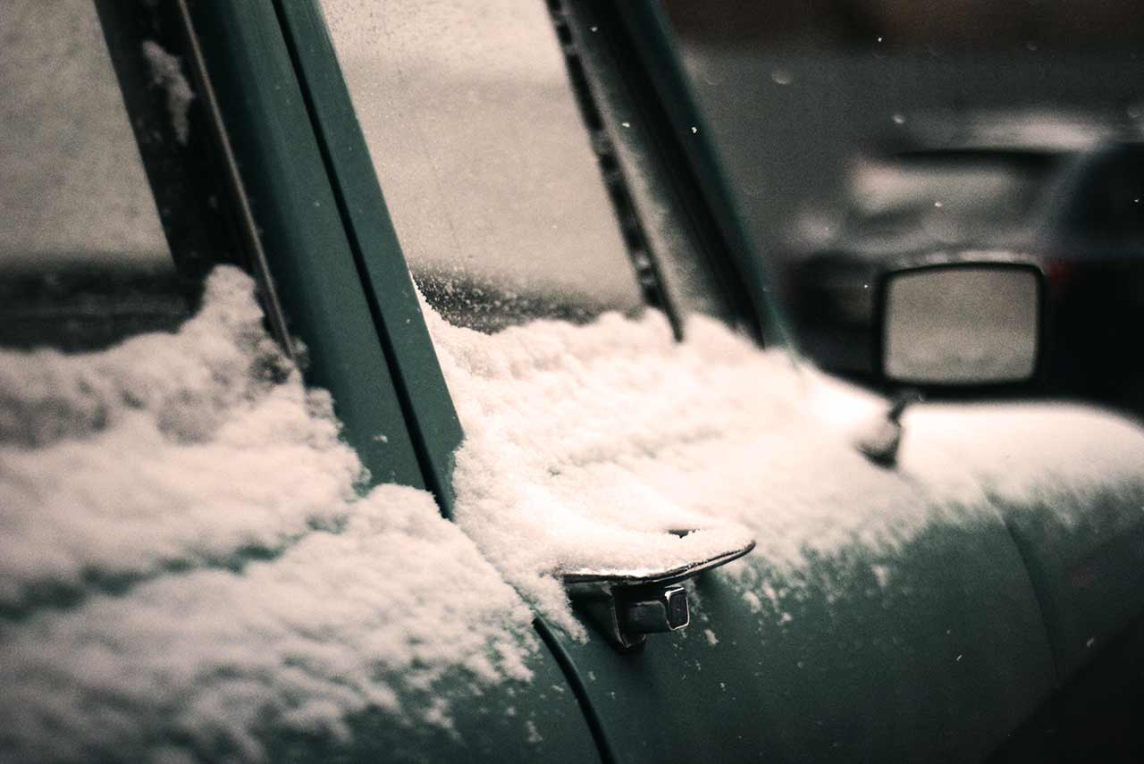 Nieve y hielo en las lunas de cristal de un coche durante el invierno sin tratamiento antilluvia